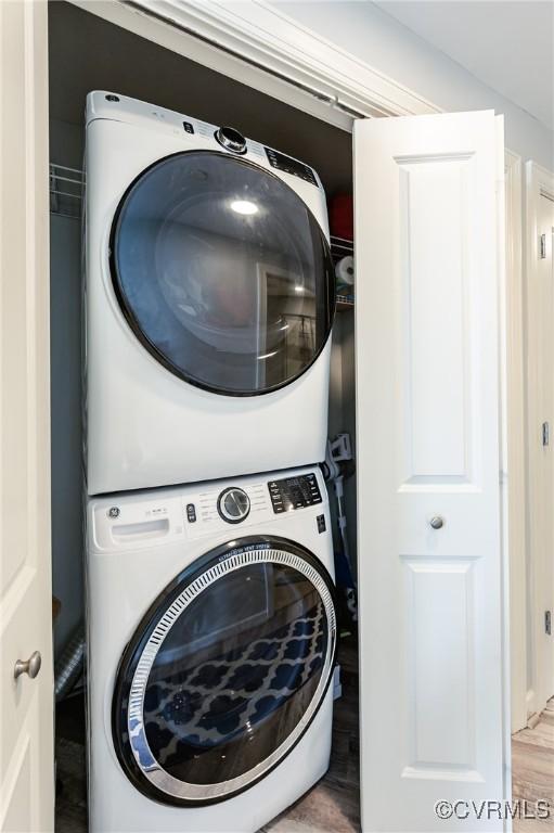laundry area featuring laundry area, stacked washer and dryer, and wood finished floors