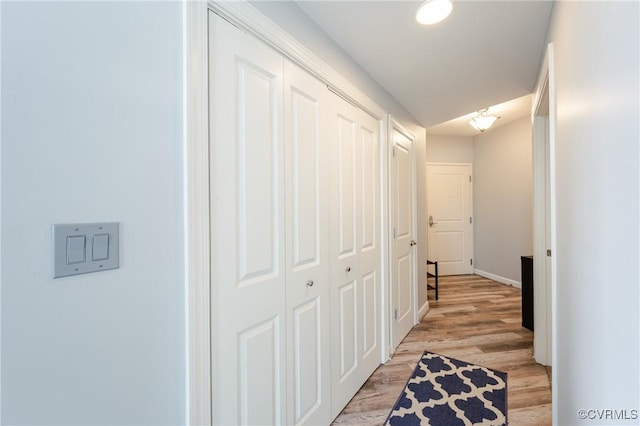 corridor with baseboards and light wood-style floors