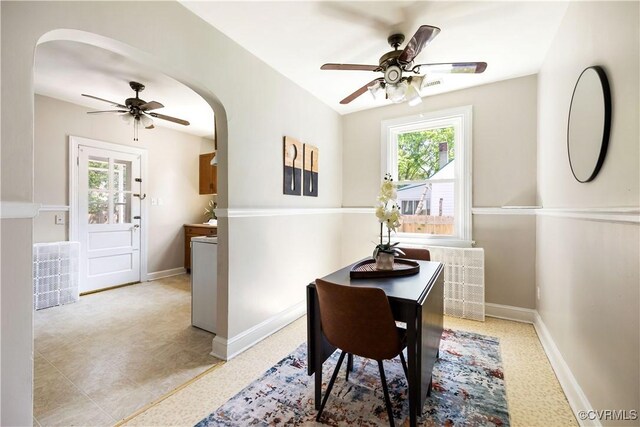 dining space with ceiling fan, plenty of natural light, arched walkways, and baseboards