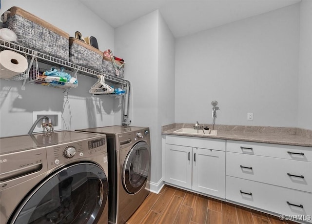 clothes washing area featuring a sink, separate washer and dryer, cabinet space, and wood finished floors