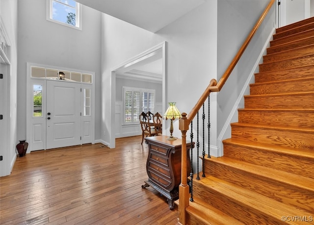 foyer featuring hardwood / wood-style flooring, a wealth of natural light, stairway, and a towering ceiling
