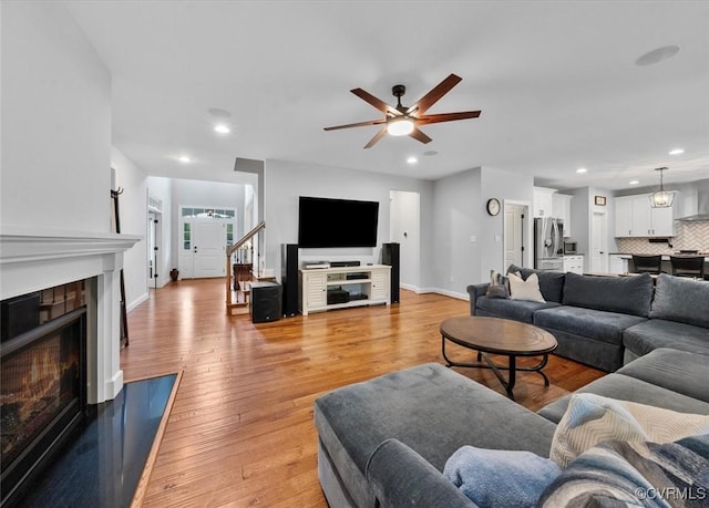 living room with a ceiling fan, light wood-style floors, recessed lighting, and a fireplace