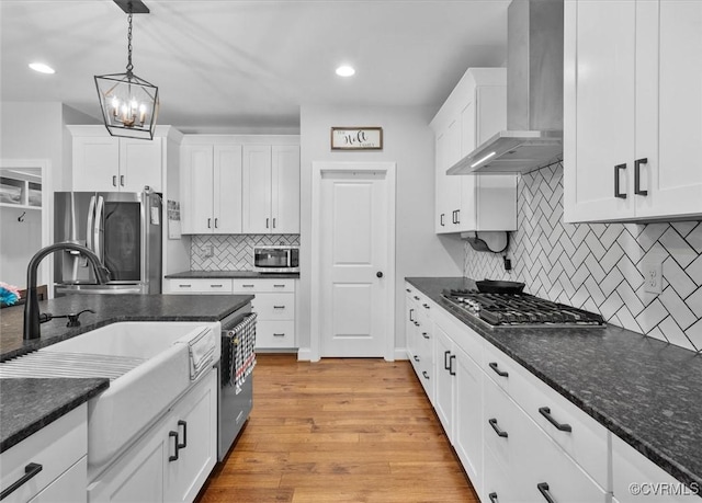 kitchen with wall chimney exhaust hood, appliances with stainless steel finishes, and white cabinets