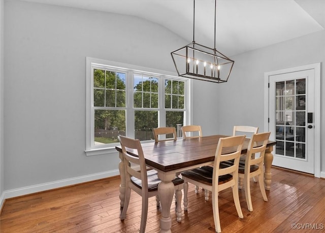 dining room with baseboards, light wood finished floors, lofted ceiling, and an inviting chandelier