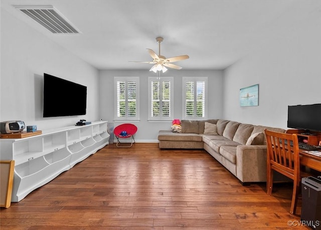 living room featuring visible vents, a ceiling fan, baseboards, and hardwood / wood-style floors