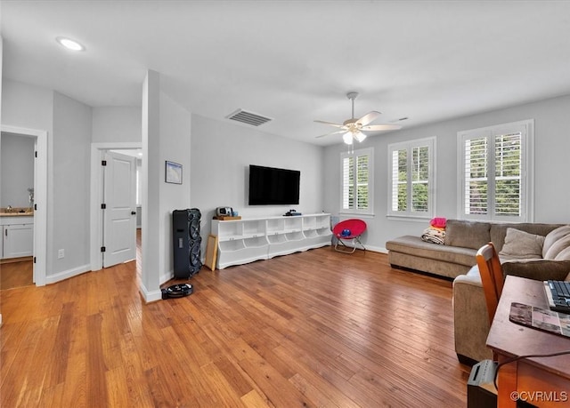 living room featuring baseboards, ceiling fan, light wood-type flooring, and visible vents