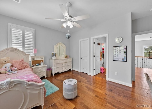 bedroom featuring baseboards, ceiling fan, wood finished floors, and a spacious closet