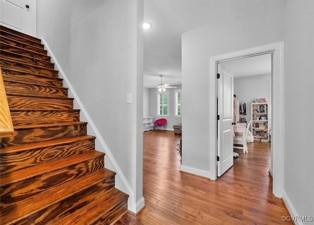 stairs featuring baseboards, ceiling fan, and wood finished floors