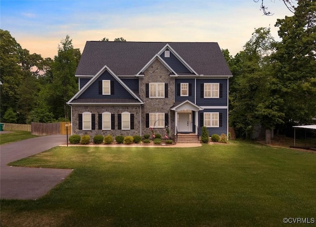craftsman inspired home with fence, a front lawn, and stone siding