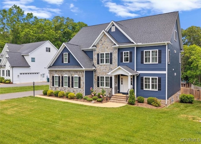 craftsman-style house featuring a garage, fence, a front yard, and stone siding