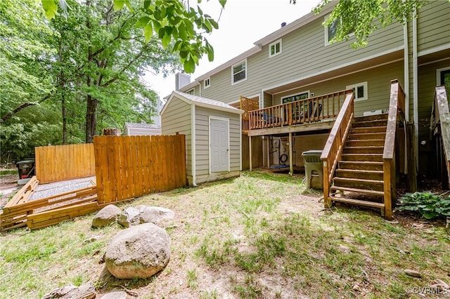 back of house featuring stairway, a wooden deck, a storage unit, an outdoor structure, and fence