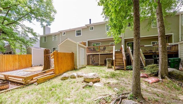 rear view of property with stairway, a deck, a shed, fence, and an outbuilding
