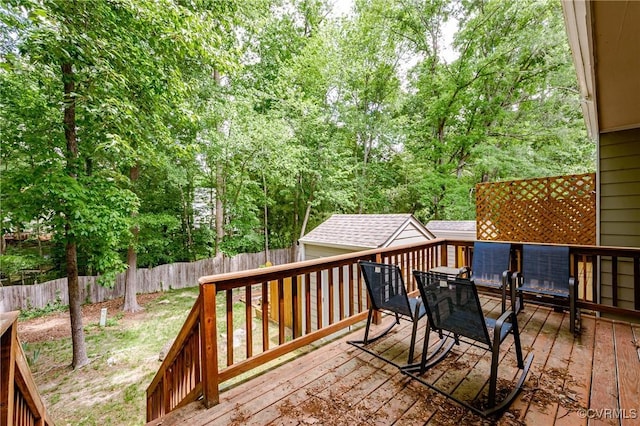 wooden terrace featuring a fenced backyard, outdoor dining area, and an outdoor structure