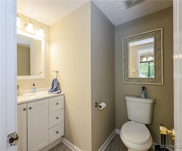 bathroom featuring baseboards, toilet, vanity, and a textured ceiling
