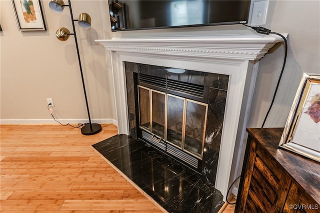 detailed view of baseboards, wood finished floors, and a tile fireplace