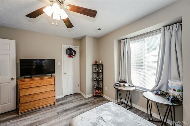sitting room featuring plenty of natural light, wood finished floors, baseboards, and ceiling fan