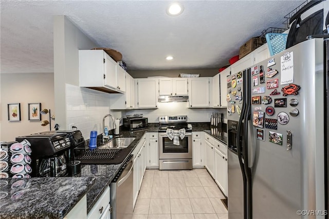 kitchen featuring stainless steel appliances, a sink, under cabinet range hood, white cabinets, and recessed lighting