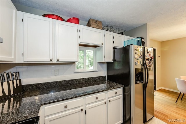 kitchen with stainless steel fridge with ice dispenser, white cabinets, dark stone counters, tasteful backsplash, and a textured ceiling