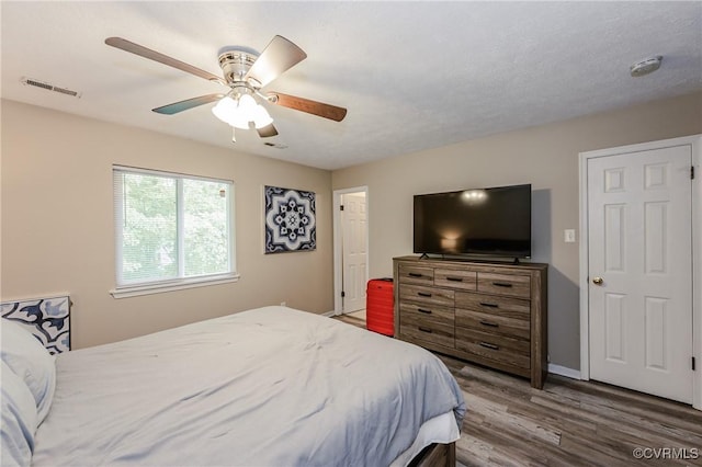 bedroom with wood finished floors, a ceiling fan, and baseboards