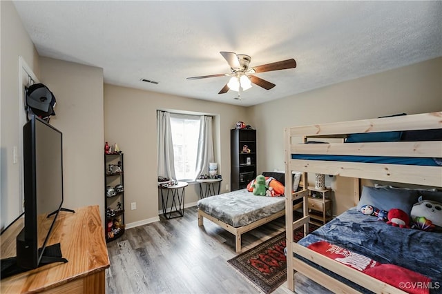 bedroom featuring wood finished floors, a ceiling fan, and baseboards