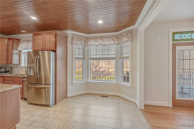 kitchen with a sink, appliances with stainless steel finishes, light stone countertops, and a wealth of natural light