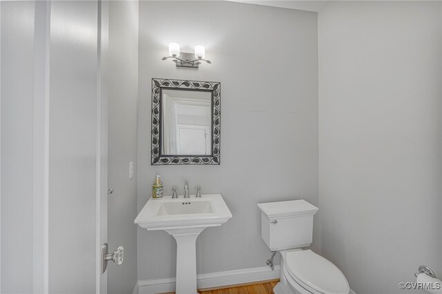 bathroom featuring baseboards, wood finished floors, and toilet