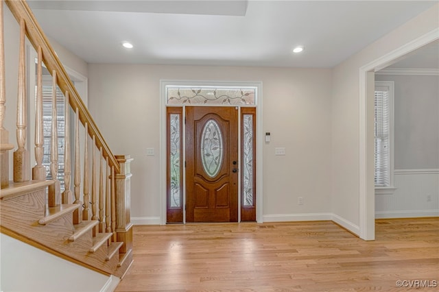 foyer entrance with stairs, baseboards, a wainscoted wall, light wood-style floors, and recessed lighting