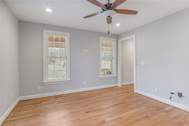 spare room featuring light wood finished floors, plenty of natural light, and baseboards
