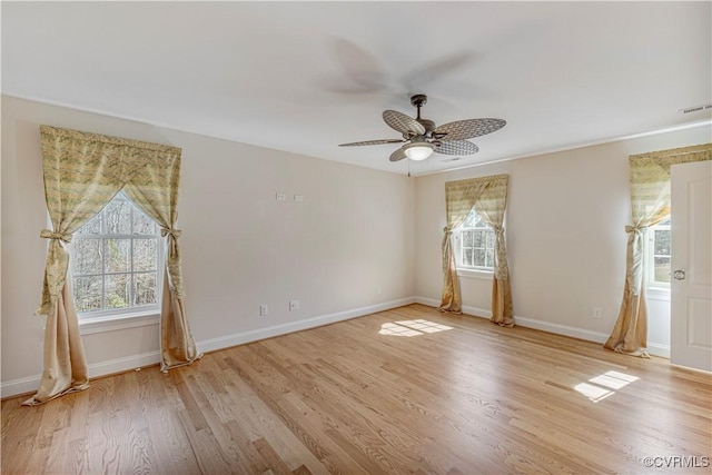 spare room with a wealth of natural light, visible vents, a ceiling fan, and light wood-style floors