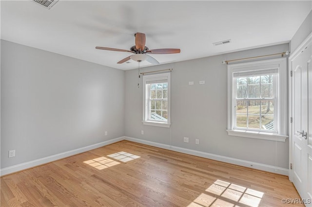 empty room featuring baseboards, visible vents, and light wood-style floors