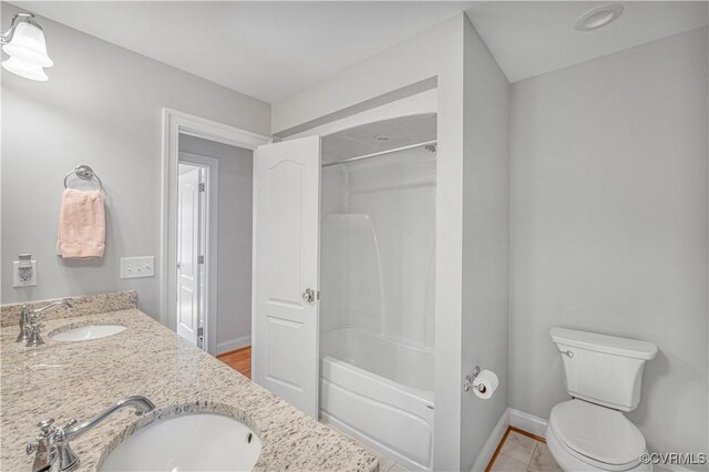 bathroom featuring toilet,  shower combination, double vanity, and a sink