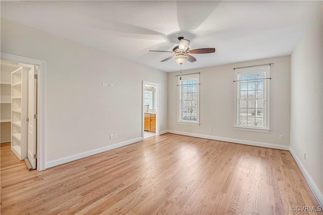 spare room with light wood-type flooring, baseboards, a ceiling fan, and a healthy amount of sunlight