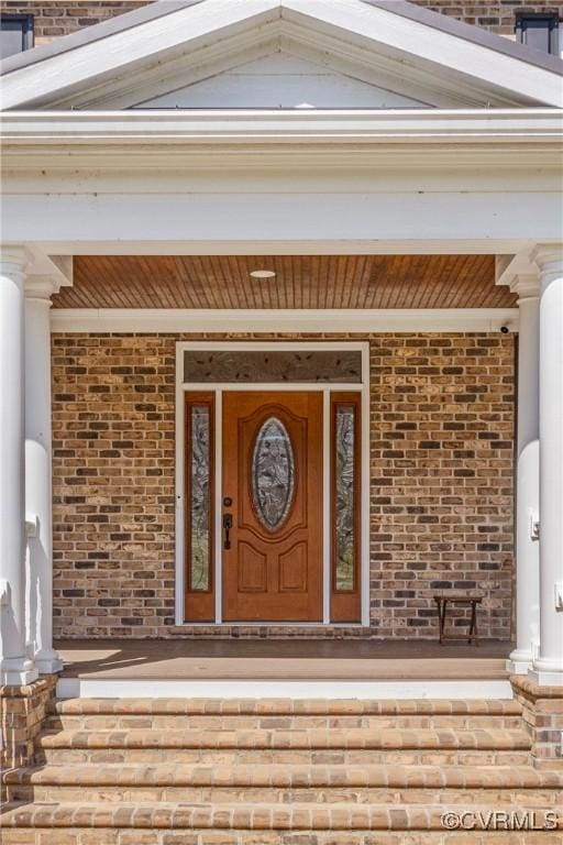 property entrance featuring a porch and brick siding