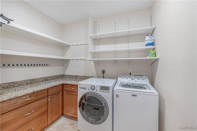 laundry room featuring washing machine and clothes dryer, light tile patterned flooring, and cabinet space
