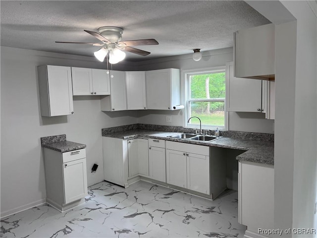 kitchen featuring white cabinets, a textured ceiling, ceiling fan, and a sink
