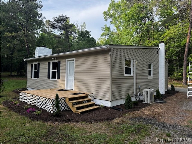 rear view of property featuring a wooden deck, a chimney, and ac unit