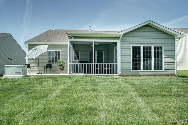 rear view of house featuring a lawn, a shingled roof, and a patio area