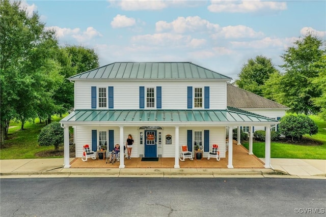 farmhouse-style home with metal roof, covered porch, and a standing seam roof