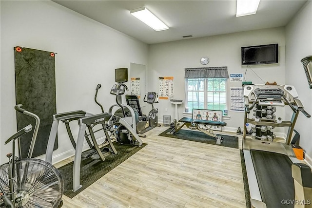 exercise room featuring baseboards, wood finished floors, and visible vents