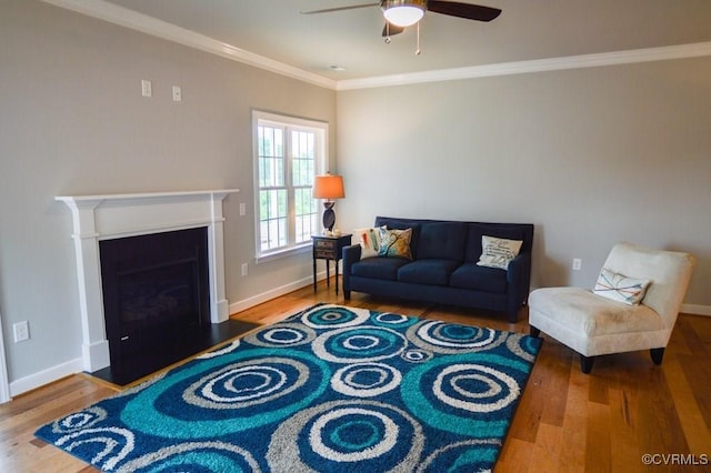 living room with crown molding, a ceiling fan, baseboards, and wood finished floors