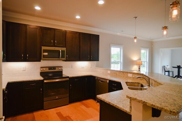 kitchen with decorative backsplash, light wood-style floors, light stone counters, a sink, and stainless steel appliances