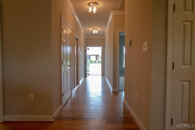 hallway featuring crown molding, baseboards, wood finished floors, and visible vents