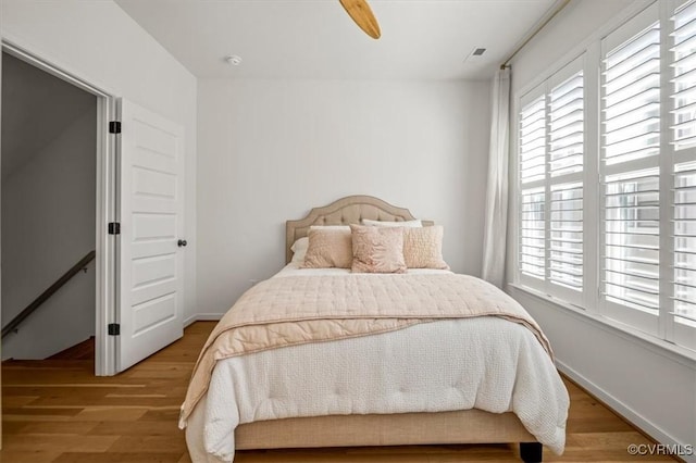 bedroom featuring baseboards, multiple windows, and wood finished floors