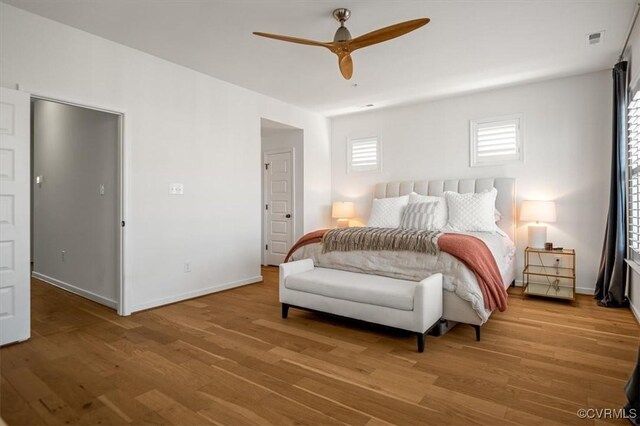 bedroom with visible vents, a ceiling fan, baseboards, and wood finished floors