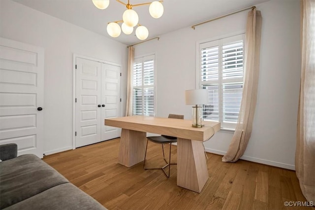 office area with baseboards, light wood-type flooring, and a chandelier