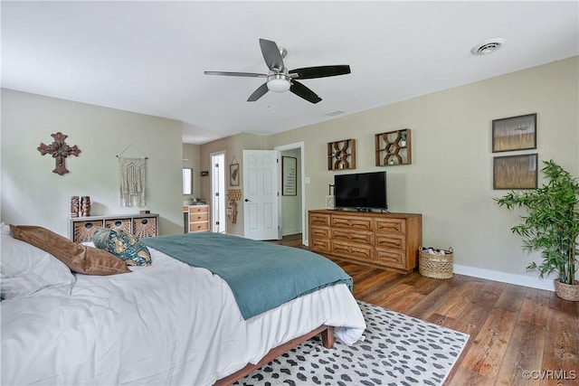bedroom with baseboards, a ceiling fan, visible vents, and wood finished floors