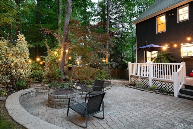 view of patio / terrace with fence, a wooden deck, and a fire pit