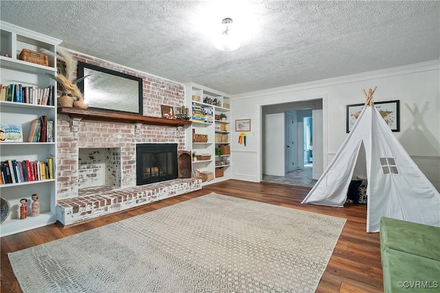 living room with built in features, crown molding, a textured ceiling, and wood finished floors