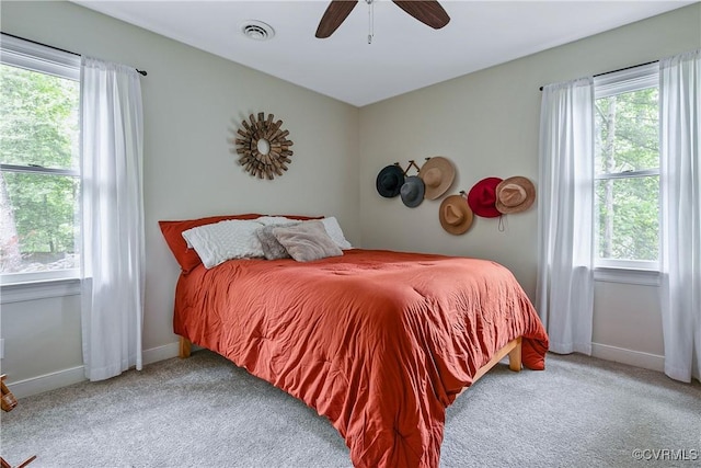 carpeted bedroom with multiple windows, visible vents, baseboards, and a ceiling fan