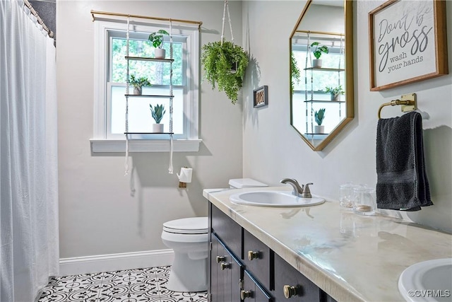 full bath featuring toilet, baseboards, a sink, tile patterned floors, and double vanity